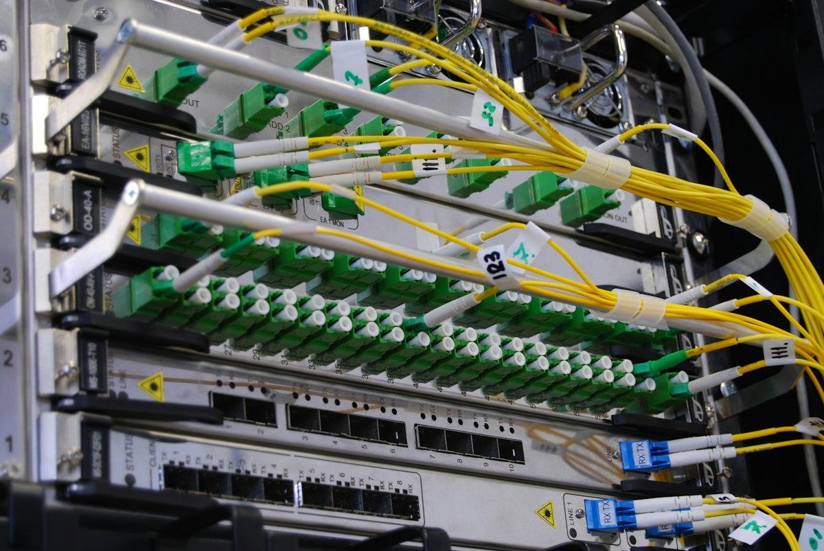 Yellow and green fibre patch leads running into the ports of a network switch